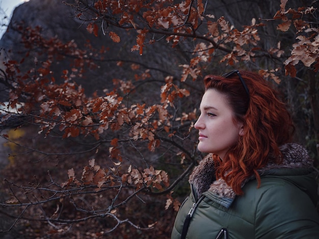 Uma mulher ruiva caminhando por uma estrada de montanha no início da primavera