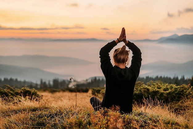 Foto uma mulher se senta em uma montanha ao nascer do sol ioga posando as mãos juntas acima da cabeça meditação fechada