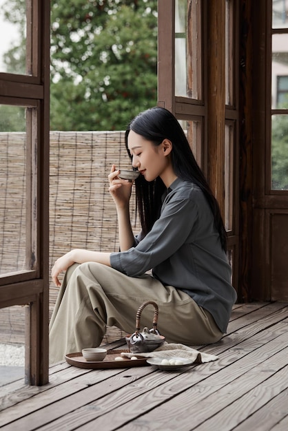 Foto uma mulher se senta em uma varanda e bebe chá.