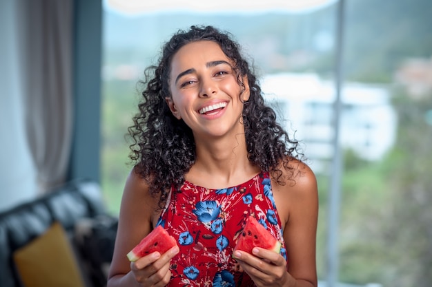 Uma mulher segura nas mãos duas fatias de melancia vermelha fresca