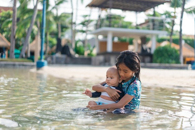 Uma mulher segura suavemente um bebê em uma piscina tranquila