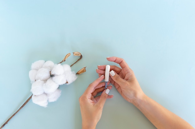 Uma mulher segura um absorvente higiênico branco nas mãos. dias de menstruação. conceito de higiene e cuidado corporal