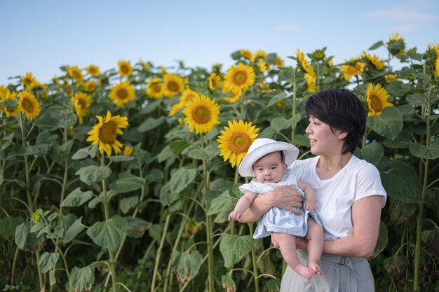 Uma mulher segura um bebê em um campo de girassóis.