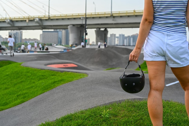 Uma mulher segura um capacete de segurança depois de andar em um parque extremo. Fechar-se. O parque de skate, patins, rampas de quarter e half pipe. Esporte radical, cultura urbana jovem para atividades de rua adolescentes.