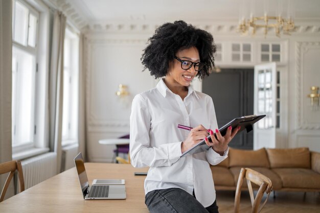 Uma mulher segura um tablet com um plano para um mês de trabalho em um novo escritório com roupas formais