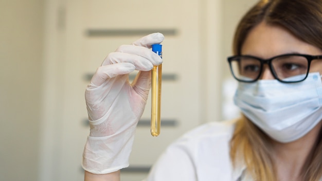 Foto uma mulher segura um tubo de ensaio com um teste de urina. conceito de diagnóstico e análise. conceito de saúde. concentre-se no tubo de ensaio