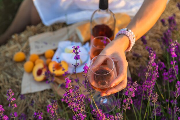 Uma mulher segura vinho em taças. piquenique no campo de lavanda. foco seletivo.