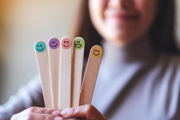 Foto uma mulher segurando a mão colorida desenha rostos de emoção feliz na vara de madeira