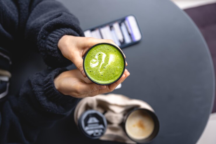 Foto uma mulher segurando nas mãos a bebida matcha verde da moda e a vista superior do smartphone