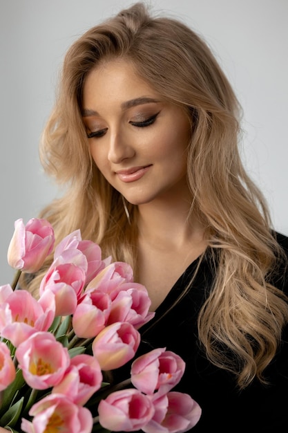 Uma mulher segurando um buquê de tulipas cor de rosa