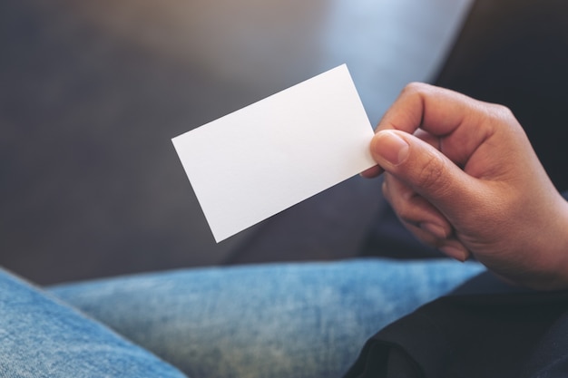 Uma mulher segurando um cartão branco vazio enquanto está sentada no escritório