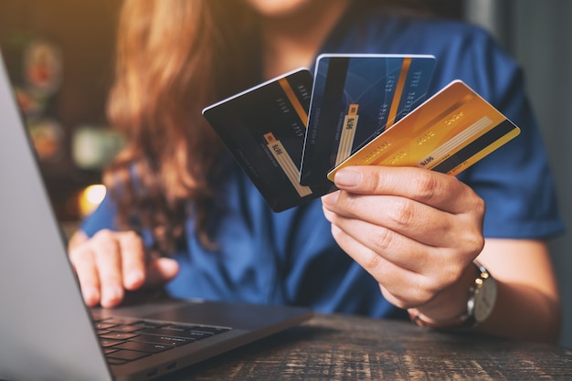 Uma mulher segurando um cartão de crédito enquanto usa um laptop