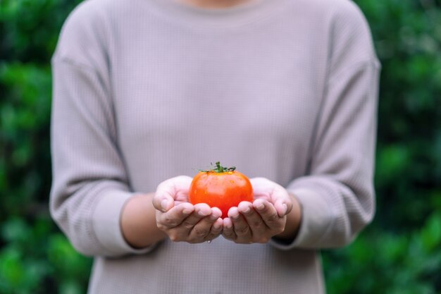 Uma mulher segurando um tomate fresco nas mãos