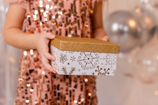 Uma mulher segurando um vestido de lantejoulas com glitter dourado e um vestido de lantejoulas com glitter dourado.