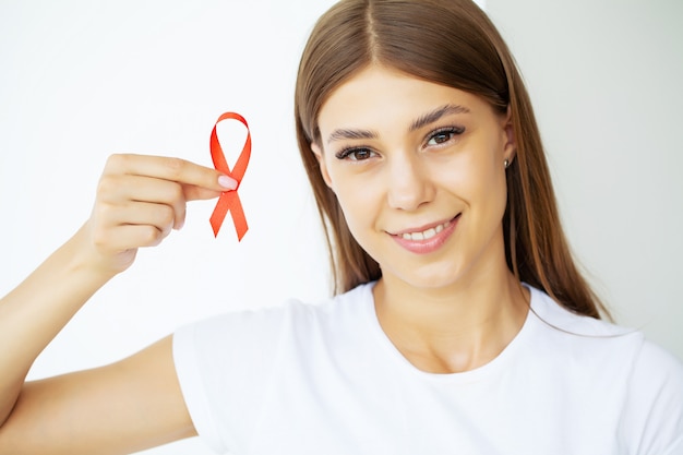 Uma mulher segurando uma fita vermelha emerge de uma situação crítica depois de superar a aids