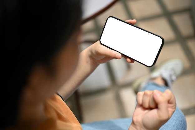 Uma mulher segurando uma maquete de smartphone e cerrou o punho enquanto está sentada ao ar livre