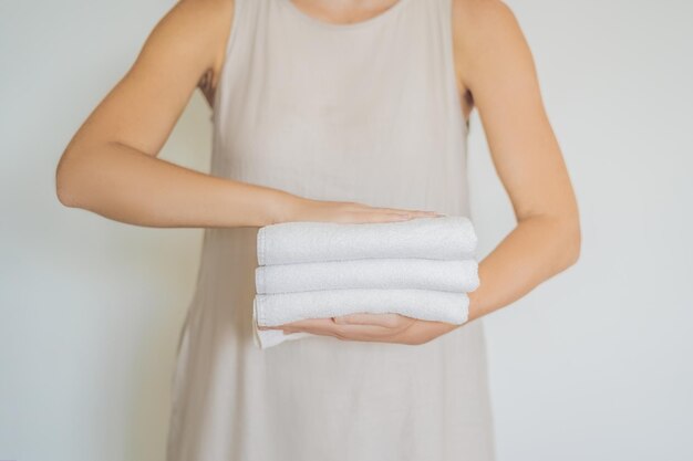 Uma mulher segurando uma pilha de toalhas brancas conceito de serviço em lavanderia spa de hotéis