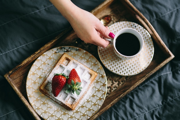 Foto uma mulher segurando uma xícara de café sobre uma bandeja