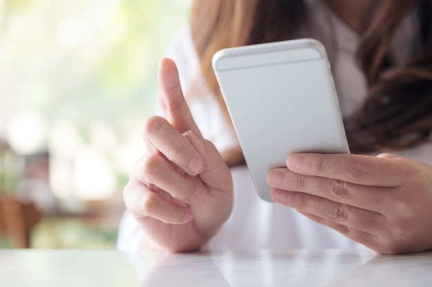 uma mulher segurando, usando e olhando para o telefone inteligente