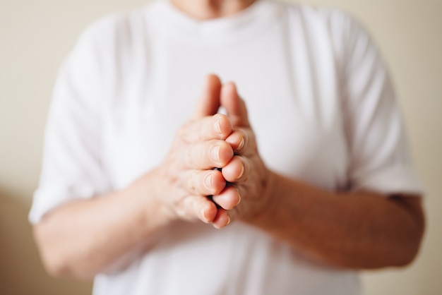 Uma mulher sênior esfrega as duas mãos. esfregue o conceito de creme para as mãos.