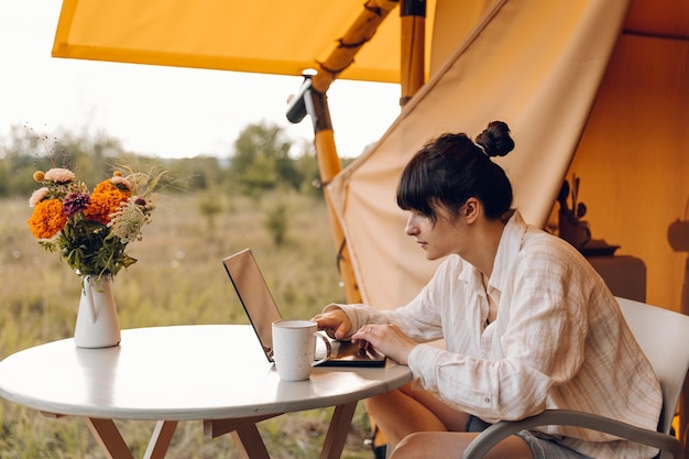 Foto uma mulher senta-se em uma mesa com um laptop e um vaso de flores