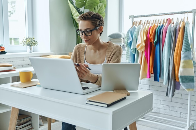 uma mulher senta-se em uma mesa com um laptop e uma camisa que diz que ela é uma marca de moda