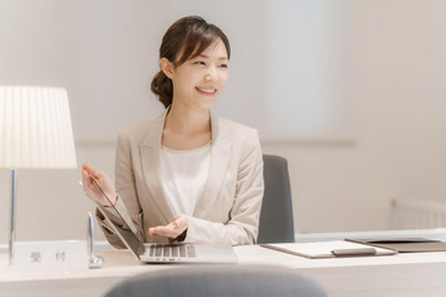 uma mulher senta-se em uma mesa com um laptop e uma caneta na mão
