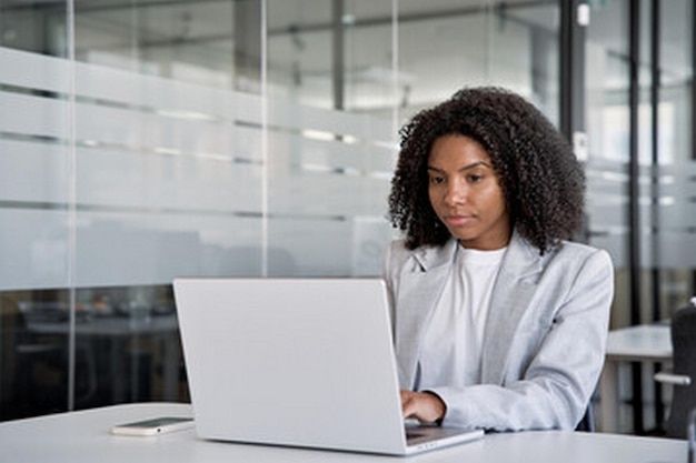 uma mulher senta-se em uma mesa com um laptop no colo