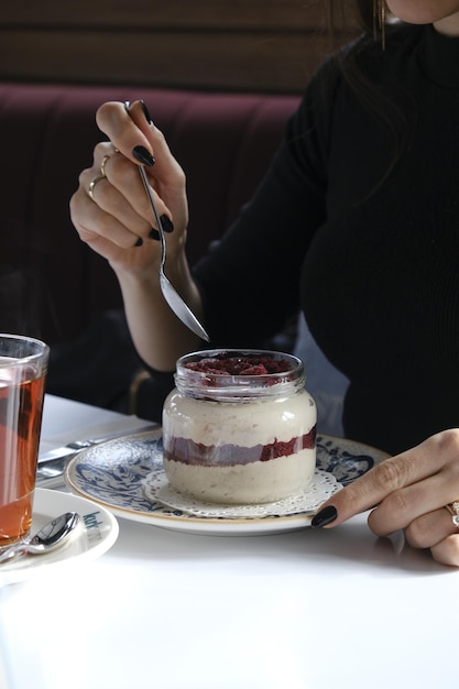 Foto uma mulher senta-se em uma mesa com uma chávena de chá e um prato de creme de chocolate