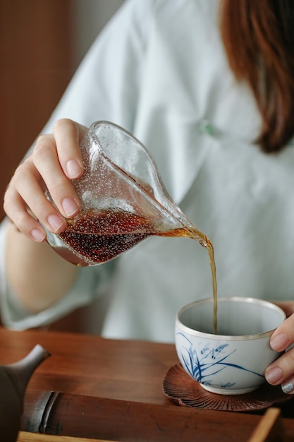 Uma mulher servindo uma xícara de chá de um bule arte minimalista de fazer chá