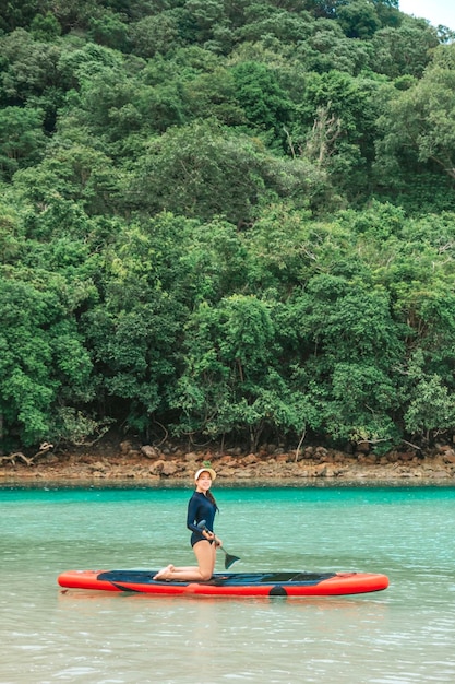 Foto uma mulher solteira remando no meio do mar apreciando a vista azul do oceano na praia fotos de viagens e relaxamento no mar da tailândia