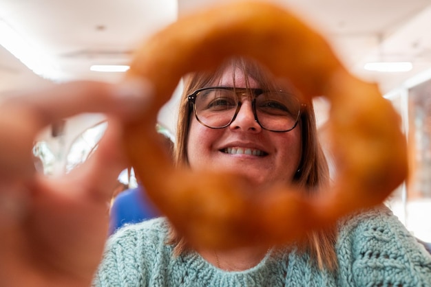 uma mulher sorri através de um picaron uma sobremesa típica peruana