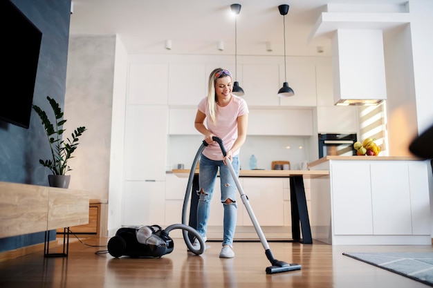 Uma mulher sorridente aspirando o chão da sala em sua casa