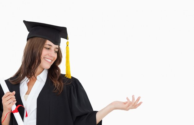 Uma mulher sorridente com um diploma enquanto abre a outra mão