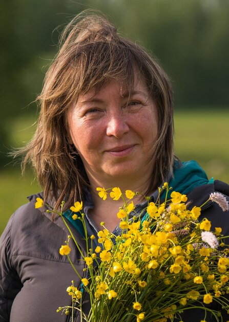 Foto uma mulher sorridente de 50 anos com um buquê de flores silvestres em suas mãos retrato em close-up