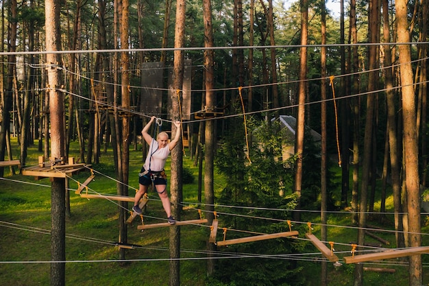 Uma mulher supera um obstáculo em uma cidade de cordas Uma mulher em um parque de cordas na floresta