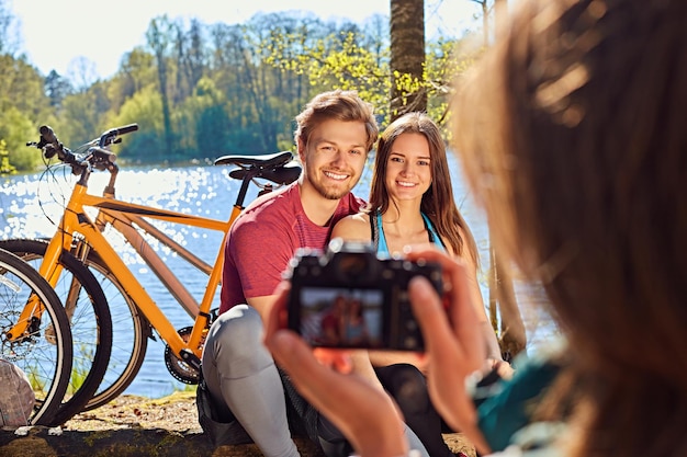 Uma mulher tirando fotos de casal desportivo após passeio de bicicleta em uma floresta.