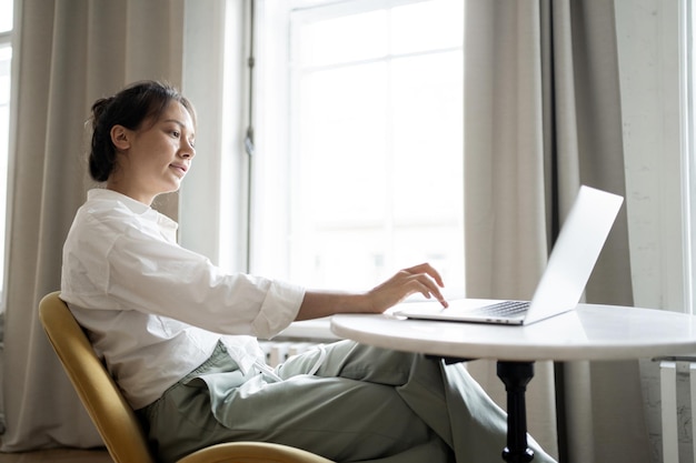 Uma mulher trabalha em casa usa um laptop faz um relatório on-line no local de trabalho