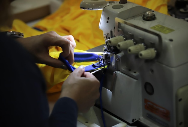 Uma mulher trabalhando com uma máquina de costura com as mãos em foco