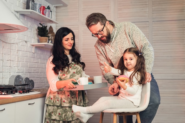 Uma mulher trata a filha e o marido com chá e donuts