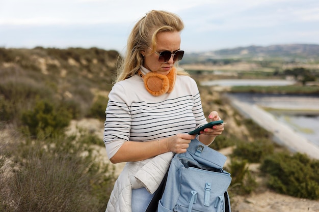 Uma mulher turista se comunica em um telefone celular no contexto da natureza