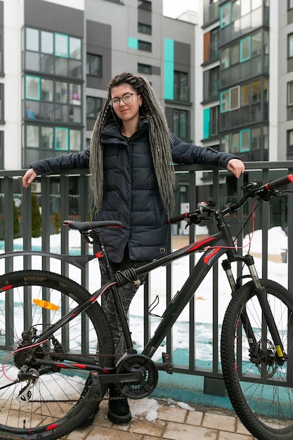 Uma mulher urbana bonita com dreadlocks alugou uma bicicleta desportiva para o fim de semana.