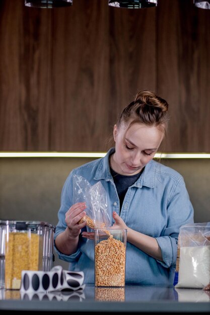 Uma mulher usa recipientes para organizar a comida na cozinha Layout e classificação de produtos alimentares Gestão da organização no interior de uma cozinha moderna Limpeza geral Limpeza na cozinha