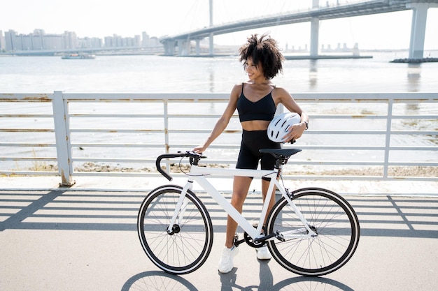 Uma mulher usa um transporte ecológico de bicicleta no treinamento cardio de fitness da cidade segura um capacete