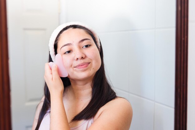 Uma mulher usa uma esponja rosa para limpar o rosto.