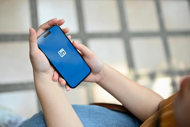 Uma mulher usando o aplicativo móvel do LinkedIn em seu telefone enquanto está sentada ao ar livre