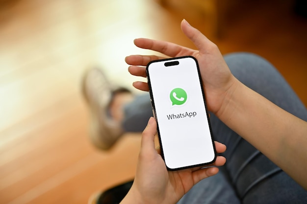 Uma mulher usando o aplicativo whatsapp em seu telefone iphone com o logotipo do whatsapp na tela