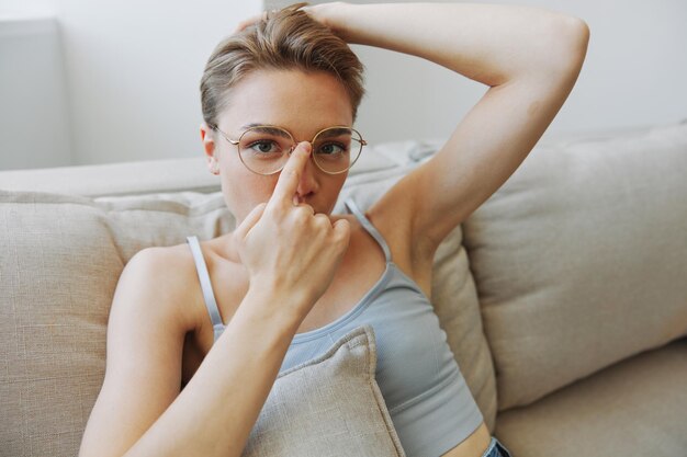 Foto uma mulher usando óculos senta-se em um sofá e olha para a câmera problemas de visão foto de alta qualidade