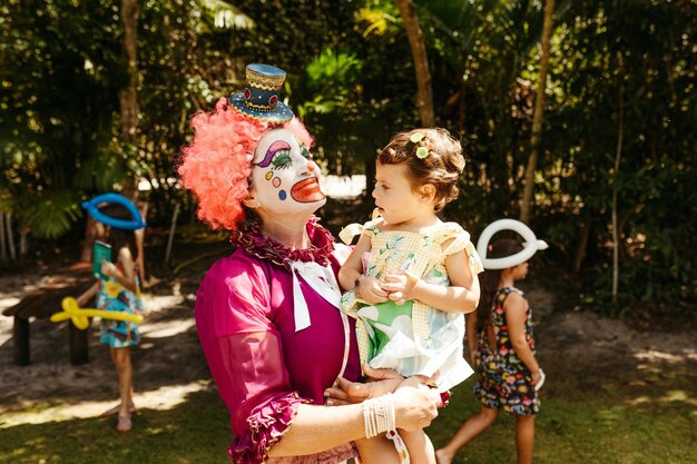 Foto uma mulher vestida de palhaço segurando uma foto de little gil