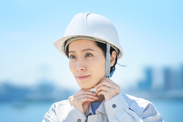 Uma mulher vestindo roupas de trabalho e verificando um capacete